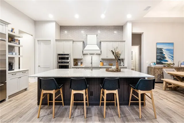 a kitchen with stainless steel appliances kitchen island granite countertop a table chairs stove and white cabinets