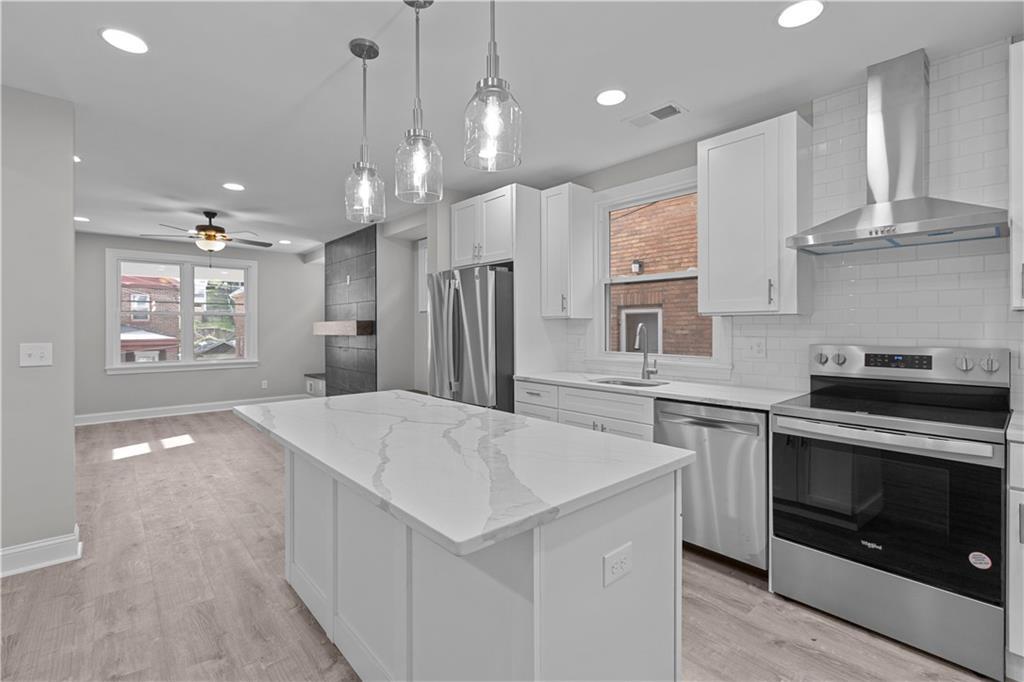 748 Anaheim Street Pittsburgh, PA 15219 - Photo 14 of 29 a kitchen with stainless steel appliances granite countertop a sink a stove a refrigerator and island with wooden floor