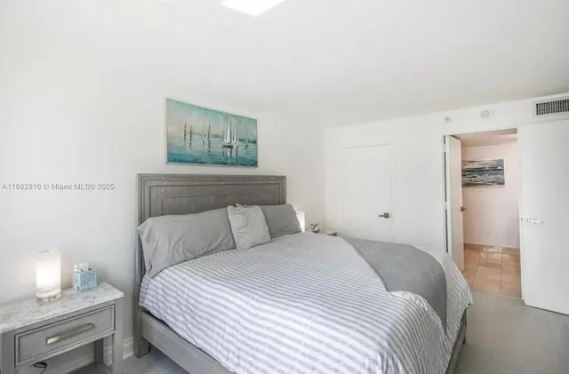 a bedroom with a bed and a lamp on the dresser