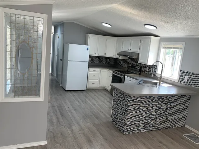 a kitchen with stainless steel appliances granite countertop a refrigerator a sink a stove a dining table and chairs