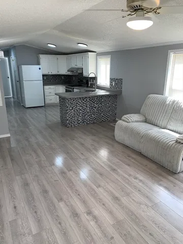 a living room with couches and kitchen view with wooden floor