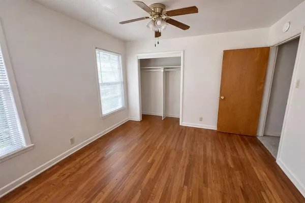 a view of an empty room with wooden floor and a window