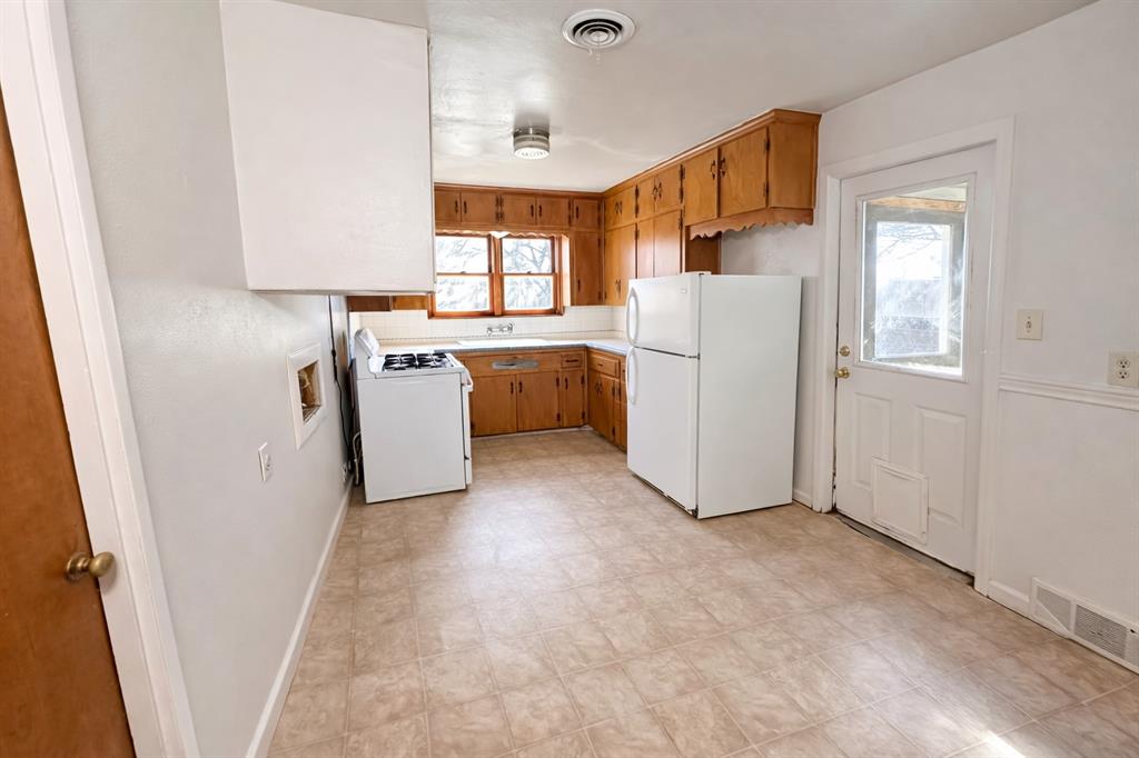 809 Crescent Street Denton, TX 76201 - Photo 9 of 24 a view of a kitchen with cabinets and a refrigerator