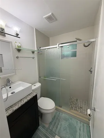 a bathroom with a granite countertop toilet and a shower