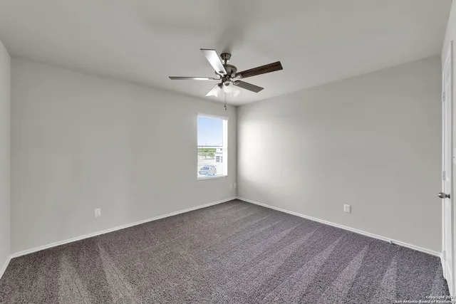 an empty room with a window and a ceiling fan
