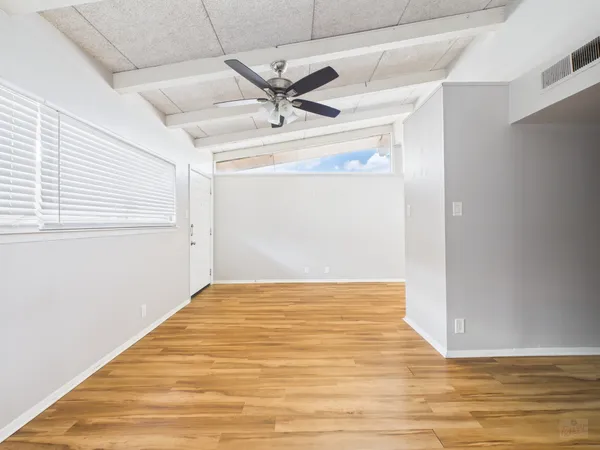 a view of empty room with wooden floor and fan
