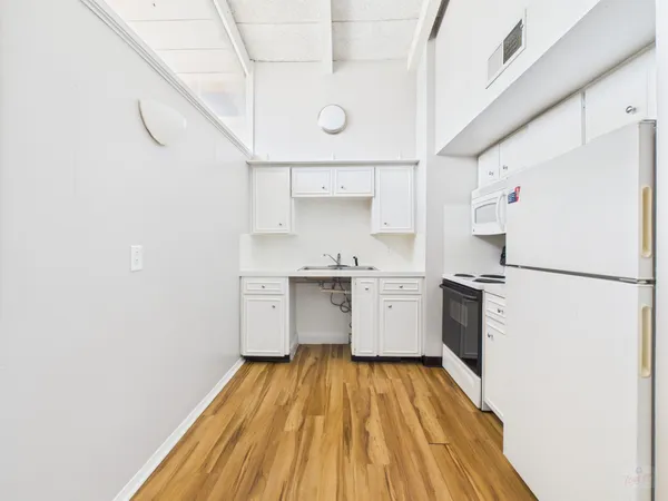 a kitchen with granite countertop white cabinets and white appliances
