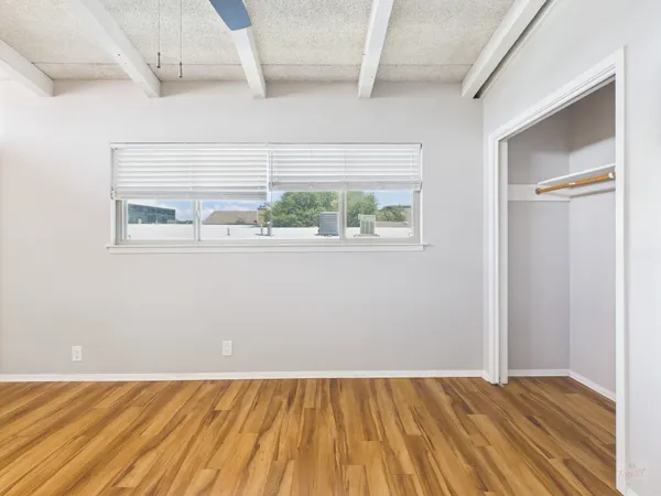 an empty room with wooden floor and windows