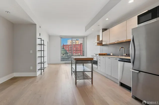 a kitchen with stainless steel appliances wooden floor and a refrigerator