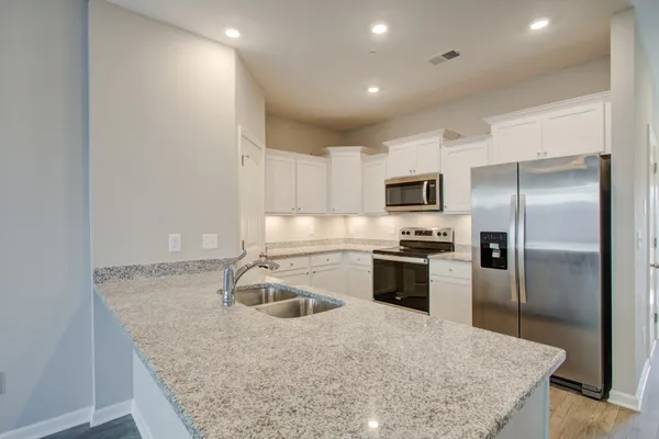 a kitchen with kitchen island granite countertop a sink stove and refrigerator