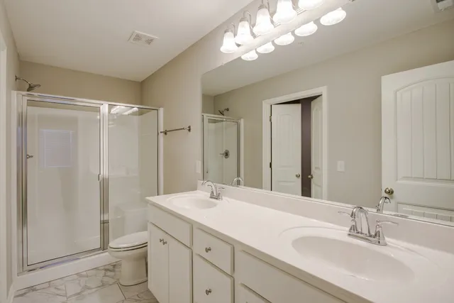 a bathroom with a double vanity sink mirror and toilet