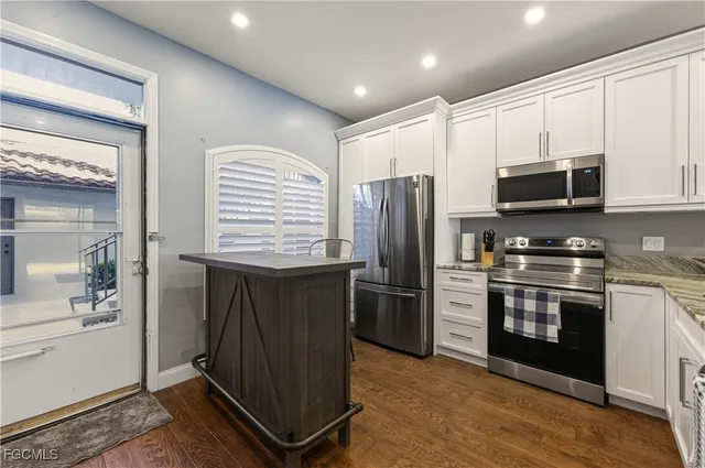 a kitchen with stainless steel appliances granite countertop a refrigerator a stove a sink and a microwave