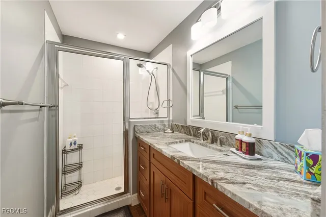 a bathroom with a granite countertop sink mirror and a shower