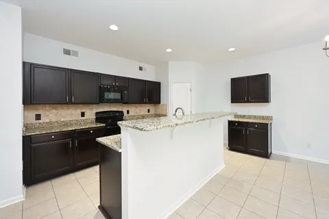a kitchen with granite countertop sink stove and microwave
