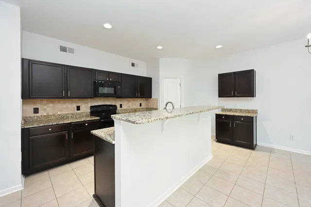 a kitchen with granite countertop sink stove and microwave