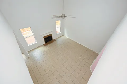 an empty room with windows and chandelier fan