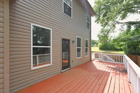 a view of a house with a wooden deck and a yard