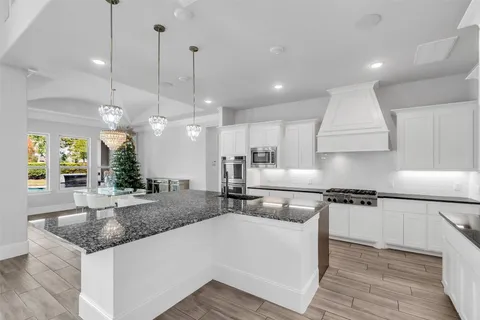a kitchen with stainless steel appliances granite countertop a sink a stove and a wooden floors