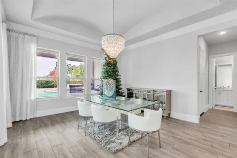 a dining room with wooden floor a chandelier a glass table and chairs