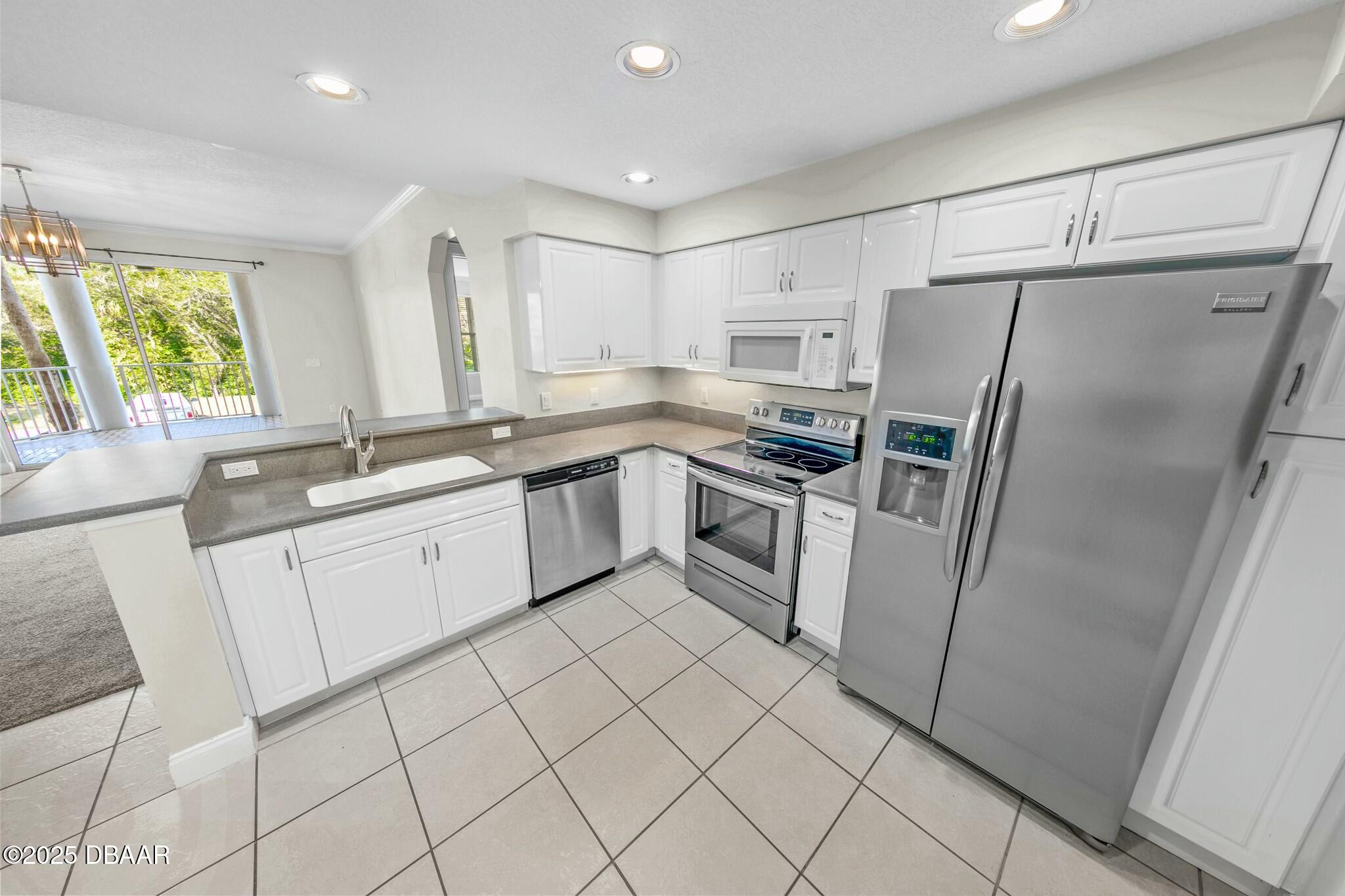 4623 Rivers Edge Village Lane, Unit 6204 Ponce Inlet, FL 32127 - Photo 8 of 51 a kitchen with cabinets a sink a window and stainless steel appliances