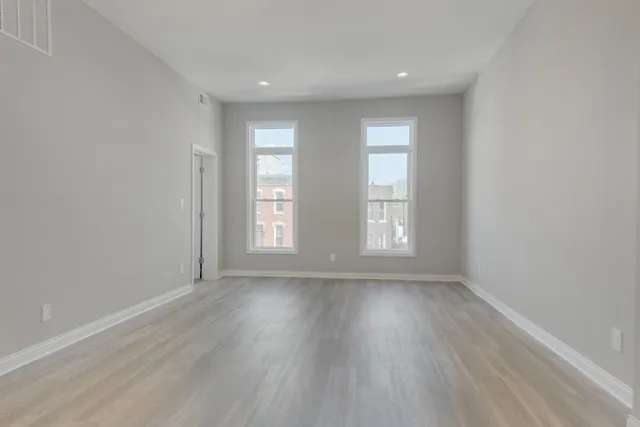 an empty room with wooden floor and windows