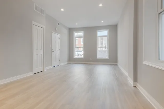 an empty room with wooden floor and windows