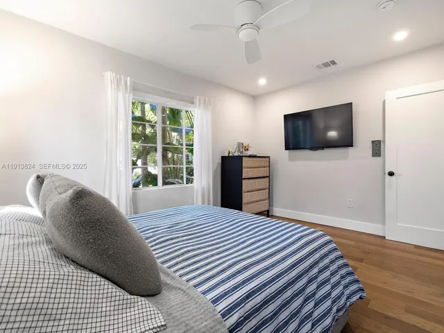 a bedroom with a bed a flat screen tv and dresser