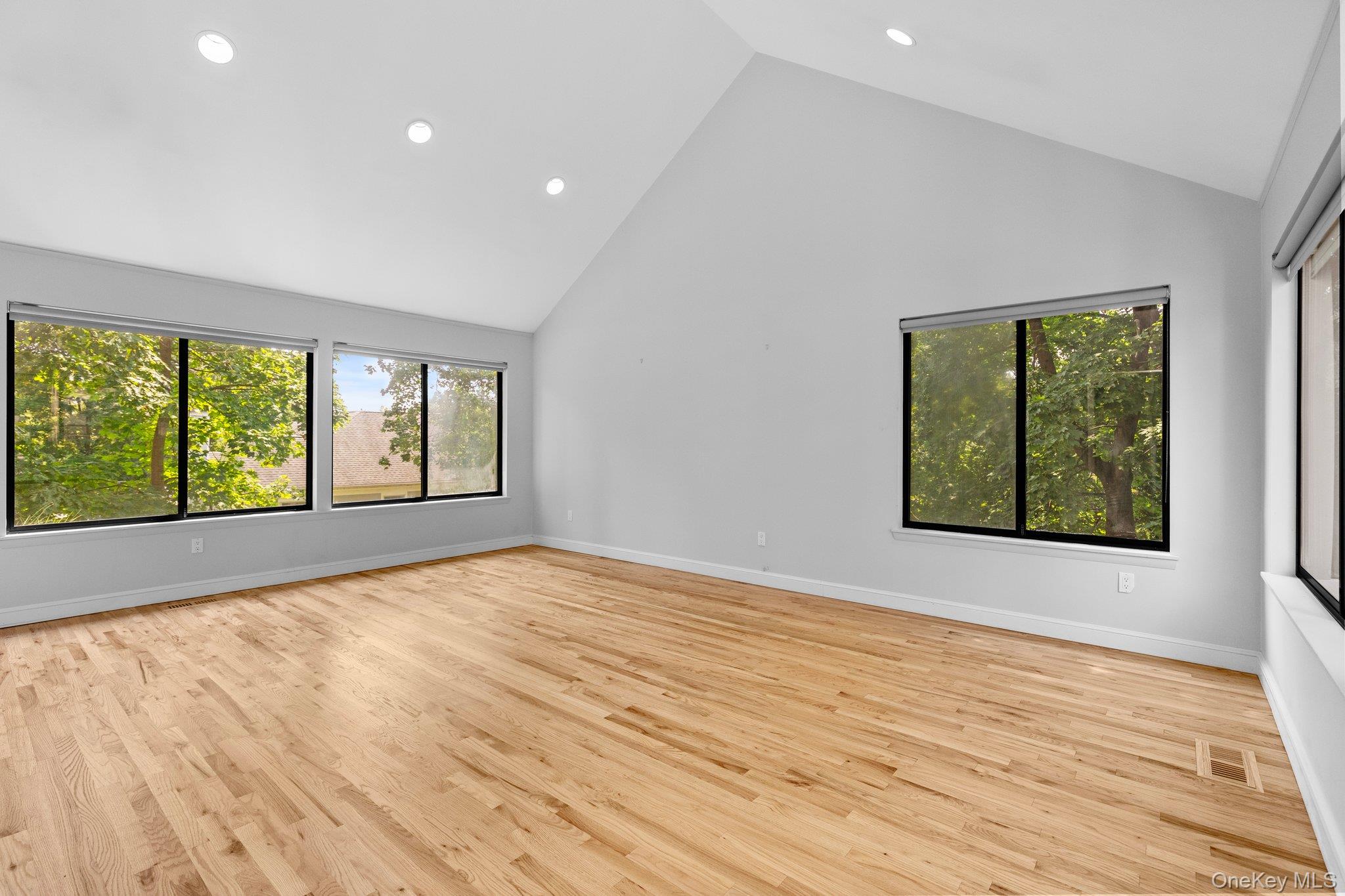 27 Stone Cabin Road New Rochelle, NY 10801 - Photo 12 of 24 Empty room featuring high vaulted ceiling, wood finished floors, baseboards, visible vents, and recessed lighting