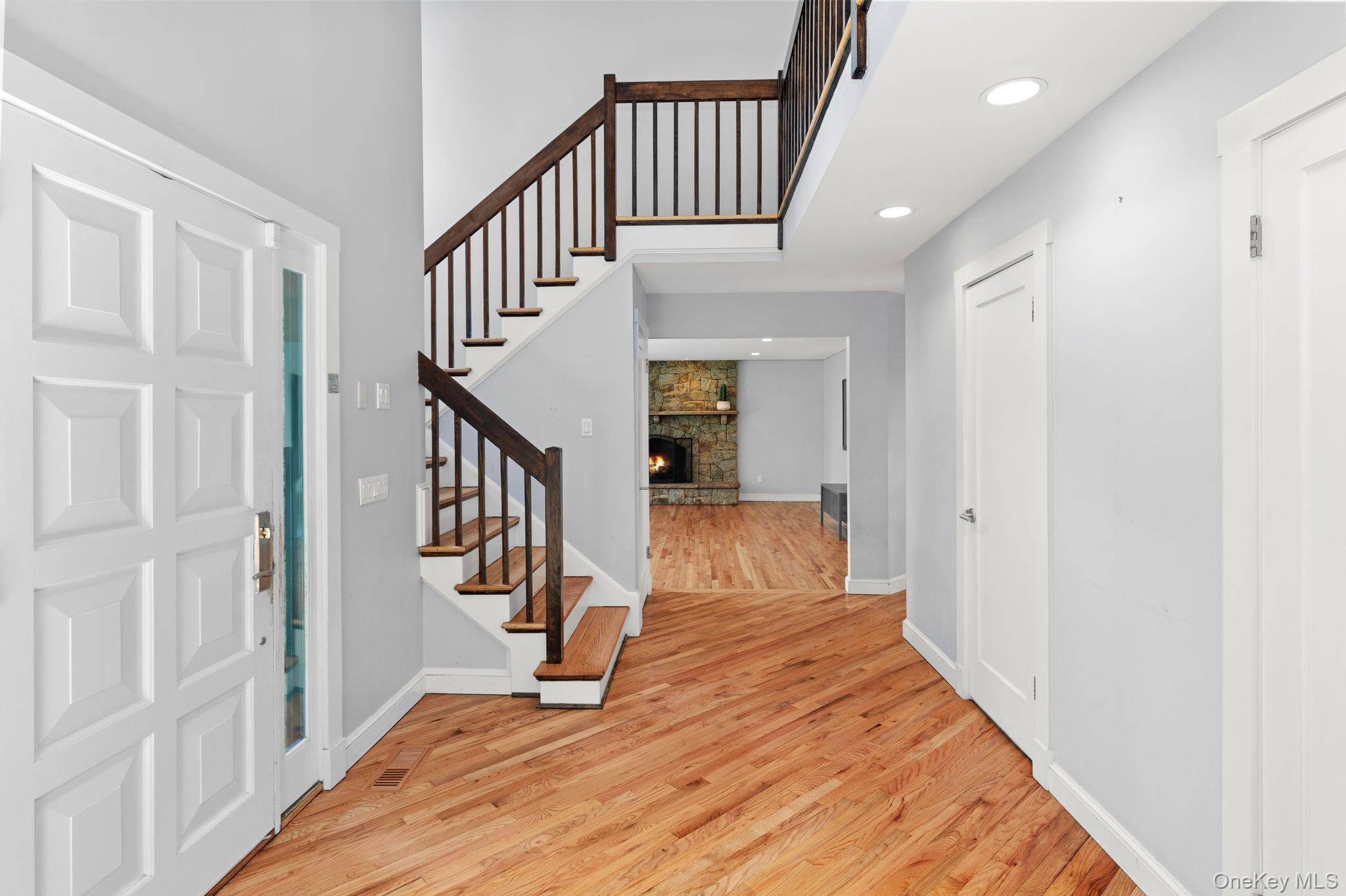 27 Stone Cabin Road New Rochelle, NY 10801 - Photo 4 of 24 Entrance foyer with light wood-style flooring, baseboards, recessed lighting, stairway, and a stone fireplace