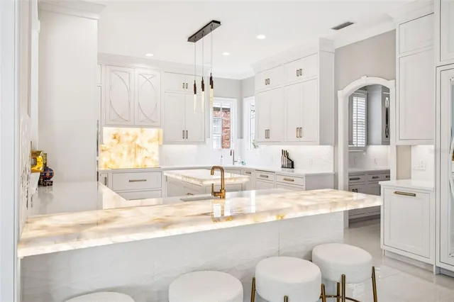 a large white kitchen with a stove a sink dishwasher and white cabinets with wooden floor