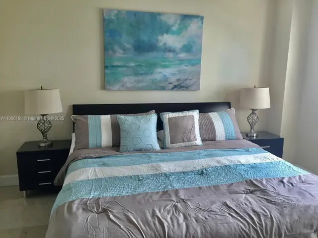 a bedroom with a bed and a lamp on dresser