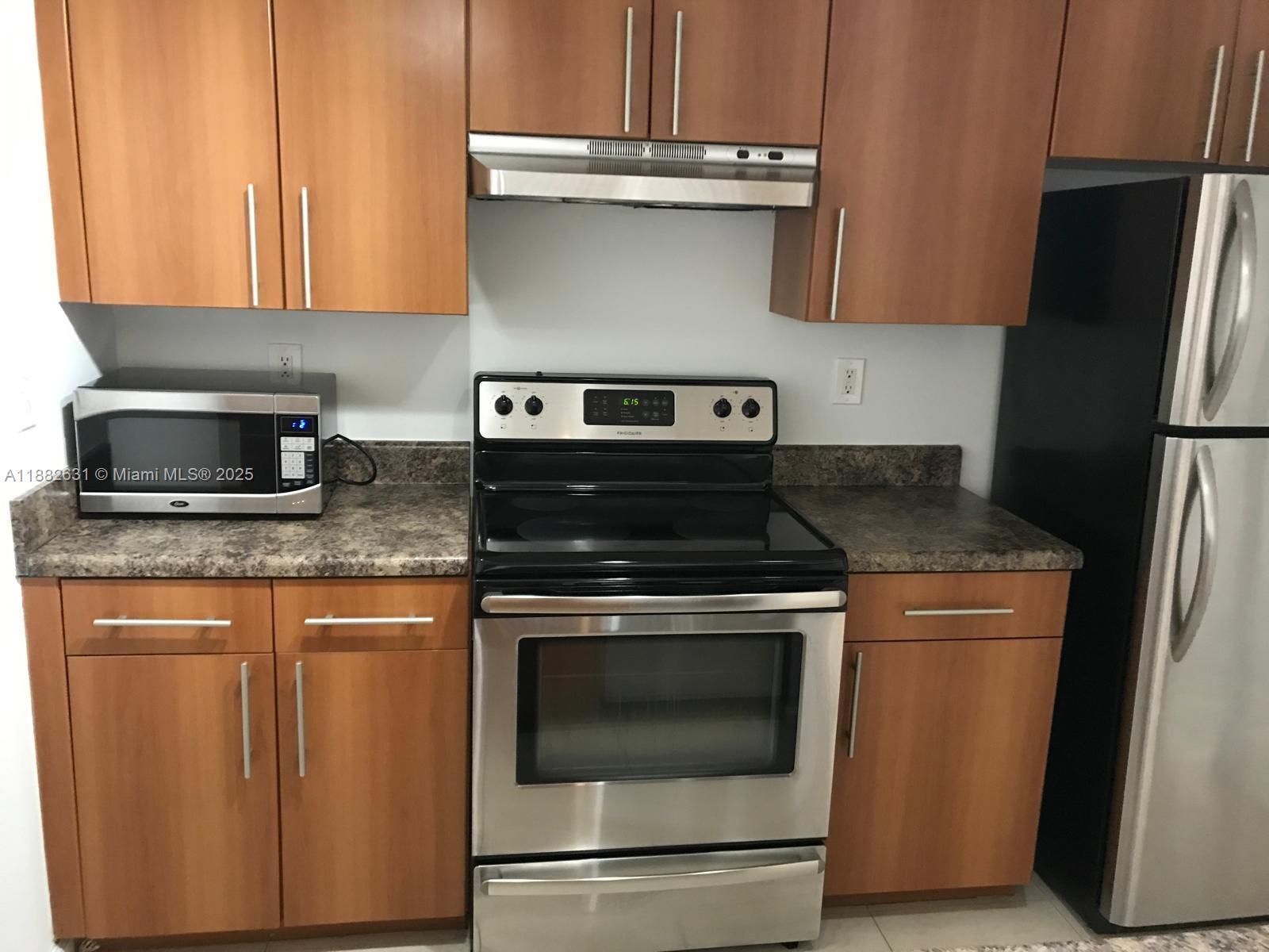 5820 West Sample Road, Unit 201 Coral Springs, FL 33067 - Photo 3 of 14 a kitchen with granite countertop a stove microwave and refrigerator