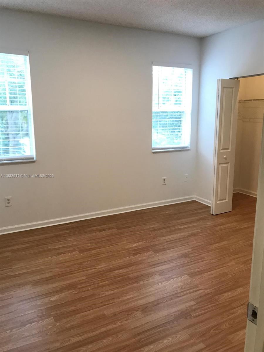 5820 West Sample Road, Unit 201 Coral Springs, FL 33067 - Photo 4 of 14 an empty room with wooden floor and windows