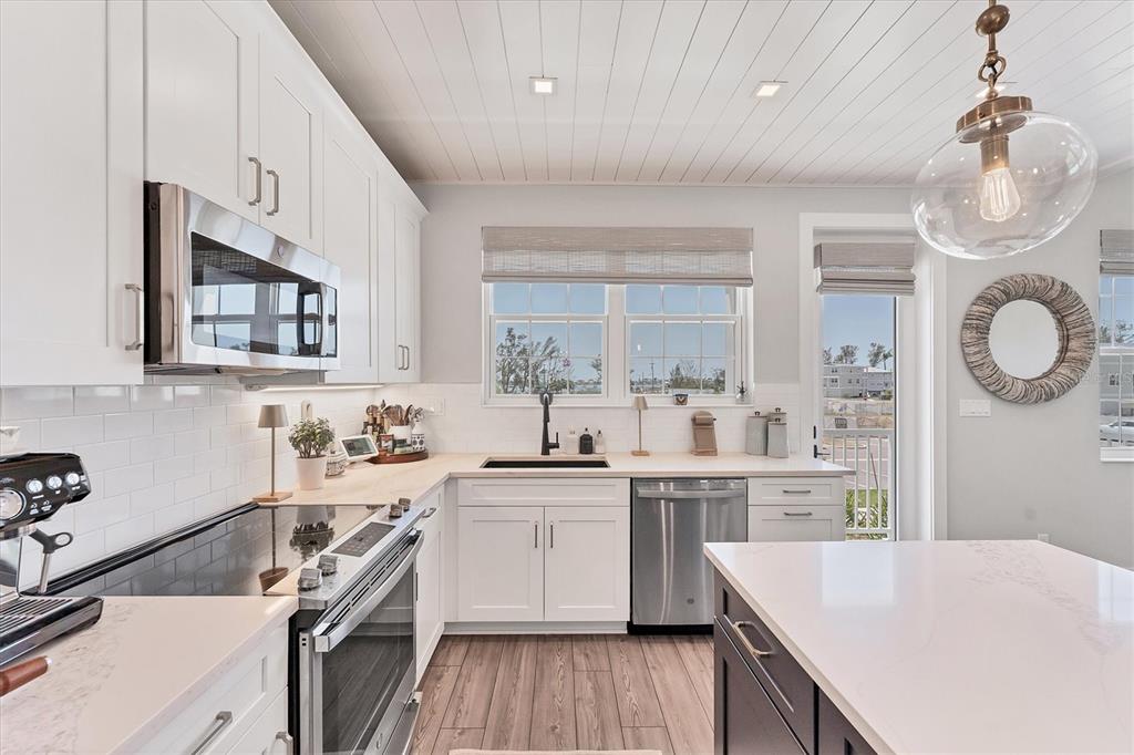 4357 Marina Vw Way Cortez, FL 34215 - Photo 25 of 59 a kitchen with a sink dishwasher a stove and white cabinets with wooden floor