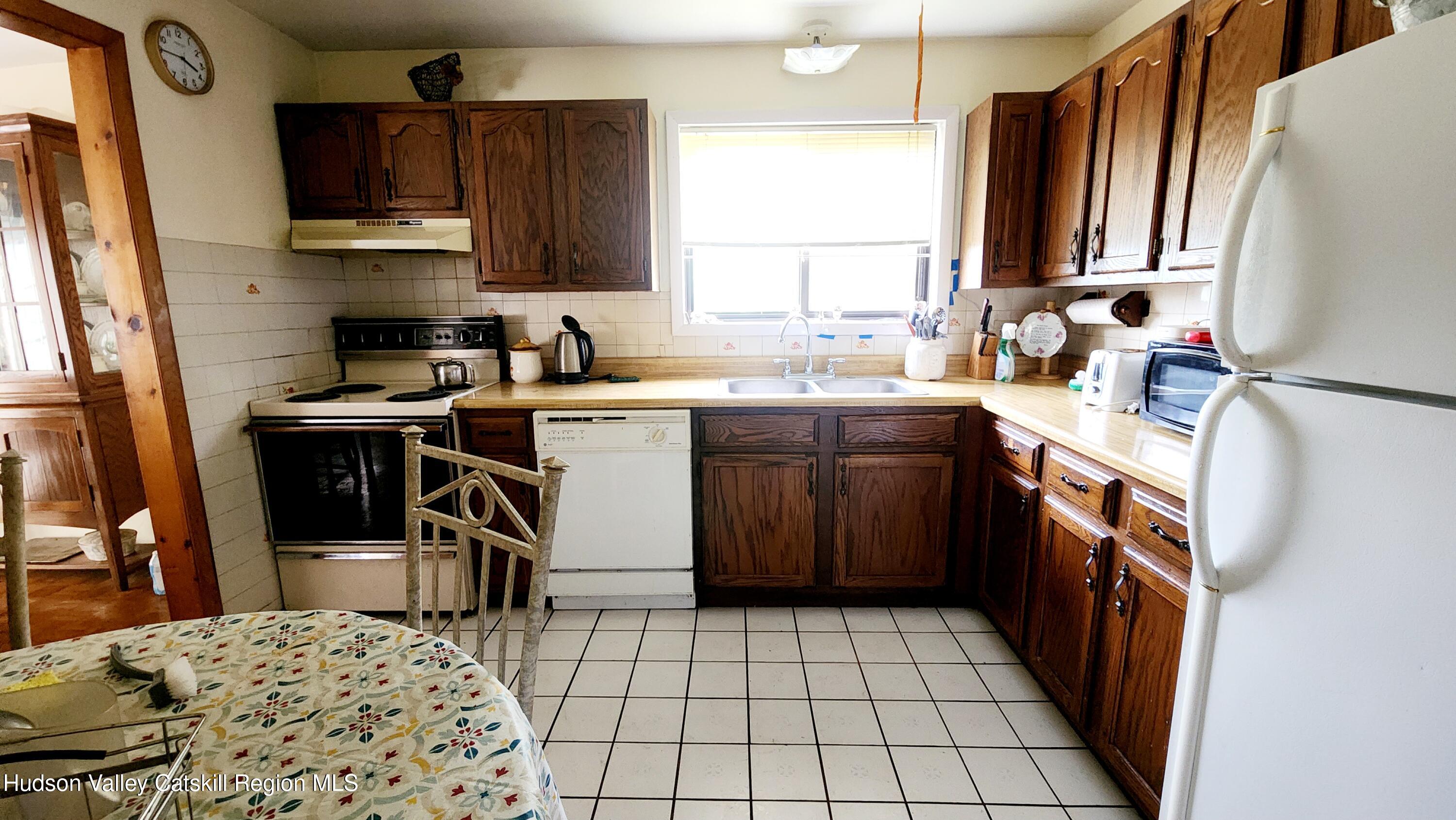 17 Clay Hill Road Durham, NY 12423 - Photo 3 of 15 a kitchen with a sink a stove a refrigerator and wooden cabinets