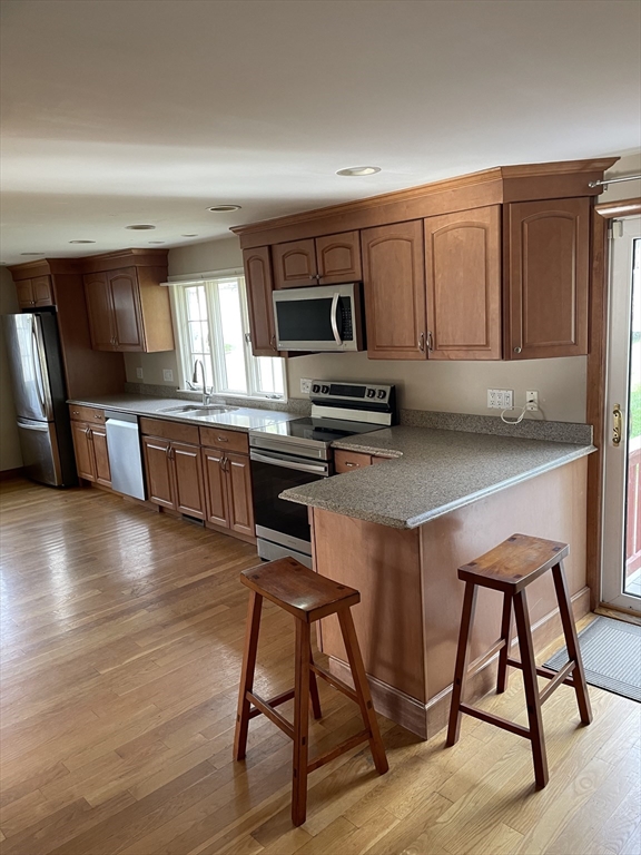 100 Francis Wyman Road Burlington, MA 01803 - Photo 3 of 17 a kitchen with stainless steel appliances wooden floors and wooden cabinets
