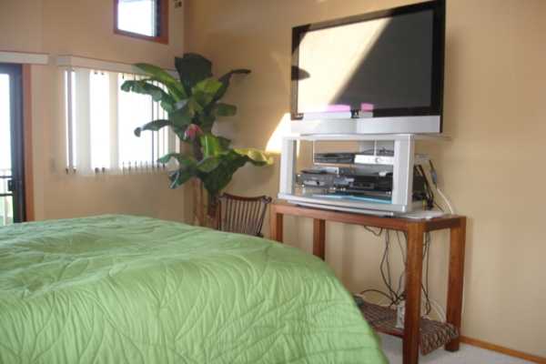 82-1064 Kiloa Road Captain Cook, HI 96704 - Photo 8 of 22 a bedroom with a bed table small window and potted plants