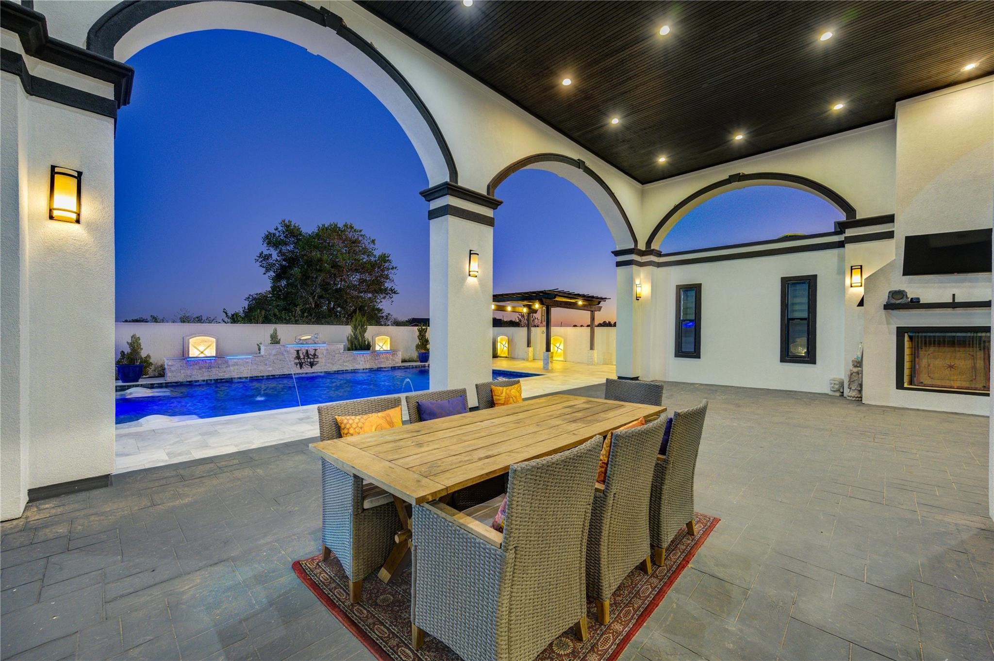 4821 Walters Road Richmond, TX 77469 - Photo 9 of 50 This stunning heated luxury pool creates a true resort-style experience with sleek modern design, expansive lounging areas, and breathtaking sunset views. Featuring elegant marble-style decking, in-water chaise loungers, ambient accent lighting, and a striking stone water feature, the space was thoughtfully designed for both relaxation and entertaining. A covered pergola lounge adds the perfect setting for evening gatherings, while the oversized pool offers a seamless blend of comfort & privacy.