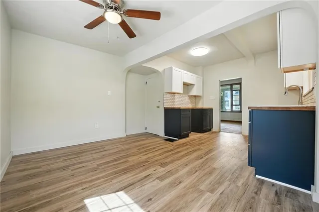 a view of kitchen and empty room with wooden floor