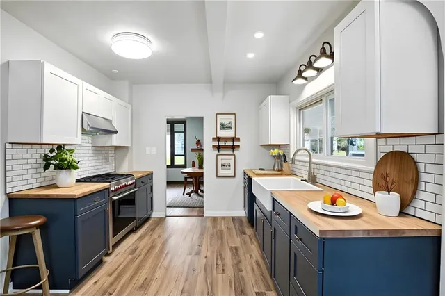 a kitchen with stainless steel appliances granite countertop a stove top oven a sink dishwasher and cabinets with wooden floor