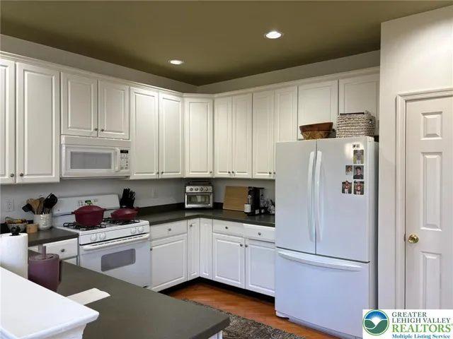 a kitchen with white cabinets and white appliances