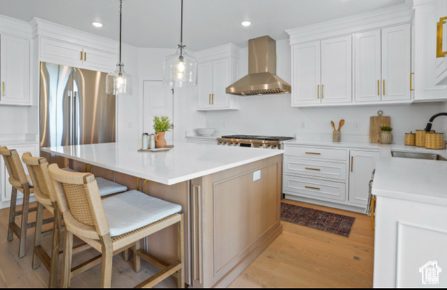 599 North Heritage Street, Unit 6 Mapleton, UT 84664 - Photo 5 of 37 Kitchen with a center island, wall chimney range hood, a kitchen bar, and white cabinetry