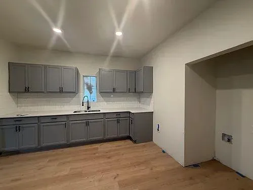 a large kitchen with granite countertop a sink and cabinets