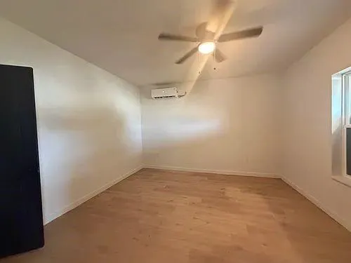 an empty room with a ceiling fan and a window