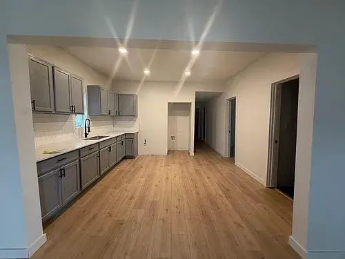 a large kitchen with a wooden floor and stainless steel appliances