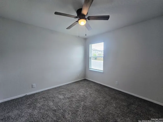 an empty room with a window and a fan