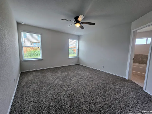 an empty room with windows and fan