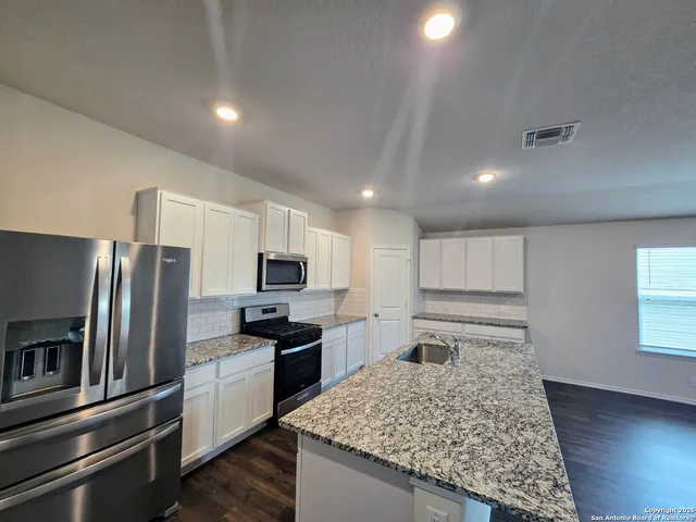 a kitchen with stainless steel appliances granite countertop a sink refrigerator and microwave