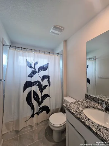 a bathroom with a granite countertop sink a toilet and a mirror