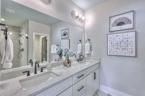 a bathroom with double vanity sinks a shower and a mirror